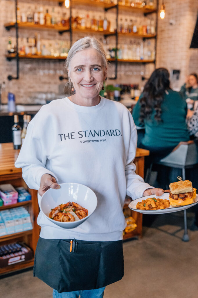Server standing in front of bar with two breakfast plates